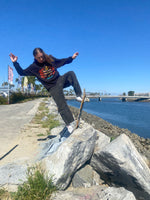 Sol Allen skateboarding on rocks by a waterfront in long beach with a clear blue sky.